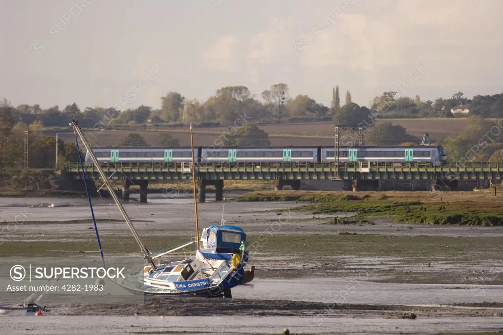 England, Essex, River Stour. A train crossing over the mudflats of the river Stour between Manningtree and Cattawade.