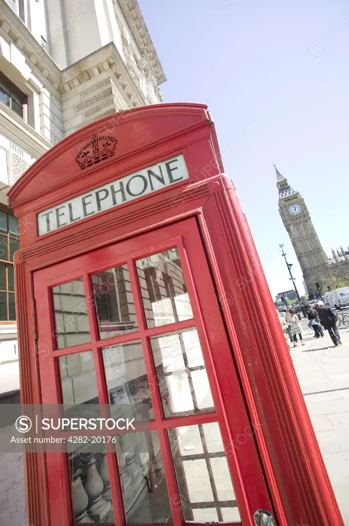 England, London, Victoria. K6 model Red Telephone box and the houses of parliament . BT replaced many of the traditional K6 boxes in the 1990s with a more modern design but not without public outcry.