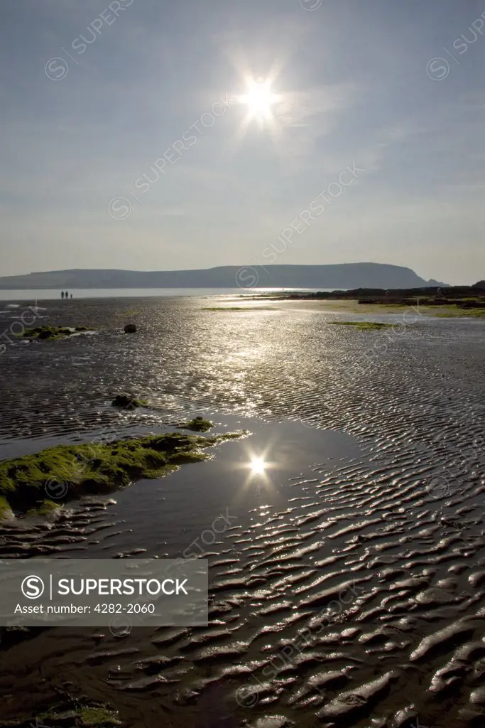 England, Cornwall, near Trebetherick. The sun reflected in a pool of water on the beach in Daymer Bay near Trebetherick, north Cornwall.