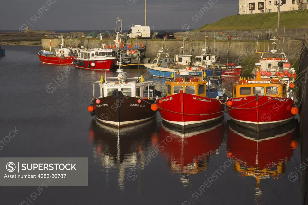 England, Northumberland, Seahouses. Boats reflected in the water in the harbour at Seahouses.