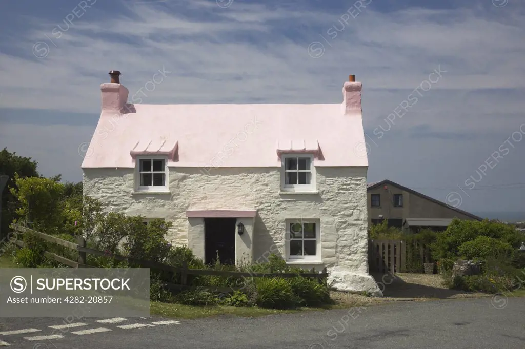 Wales, Pembrokeshire/ Sir Benfro, Near Abercastle. A stone cottage with a pink roof by a road junction.