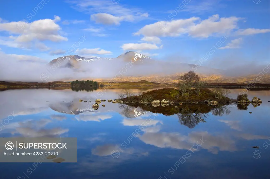 Scotland, Argyll and Bute, Rannoch Moor. Rare combination of clouds, mirror reflections, and mist slowly clearing the mountains by Lochan na h-Achlaise on Rannoch Moor.