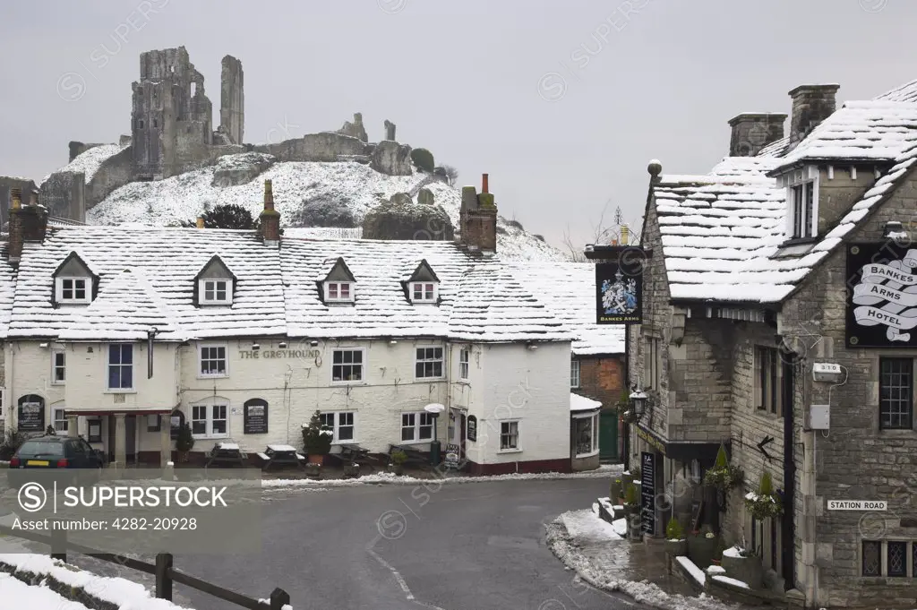 England, Dorset, Corfe Castle. The Greyhound pub, one of the most photographed pubs in England, in winter snow below Corfe Castle.