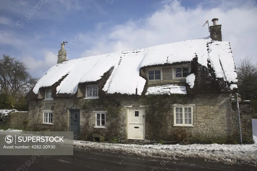 England, Dorset, Corfe Castle. Thatched Cottage in the village of Corfe Castle after a heavy snowfall.