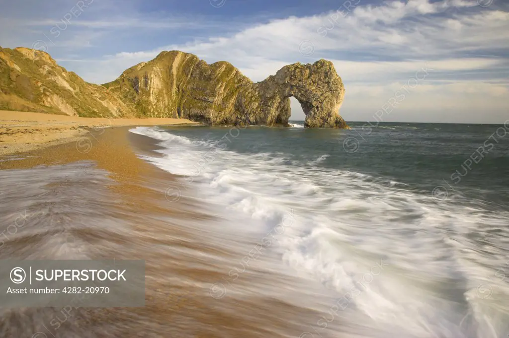 England, Dorset, Durdle Door. Waves rolling onto the beach by Durdle Door, a natural limestone arch on the Jurassic Coast in Dorset.