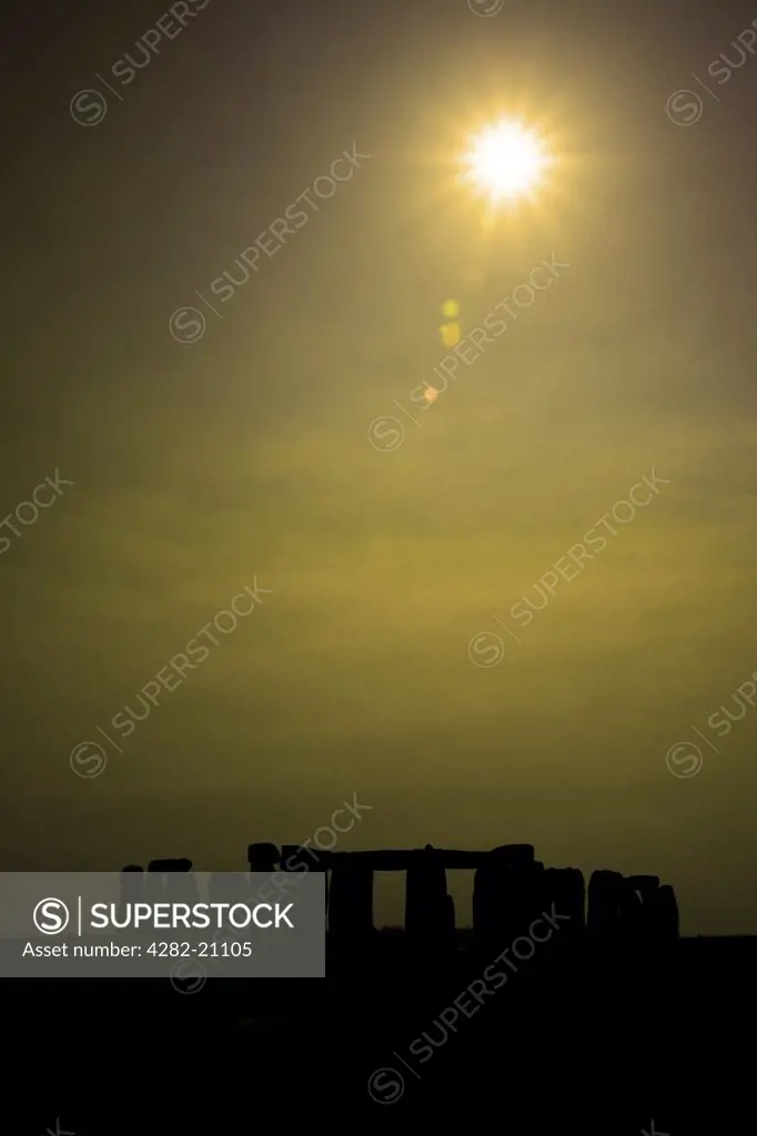 England, Wiltshire, Stonehenge. Sunlight breaking through mist over Stonehenge.