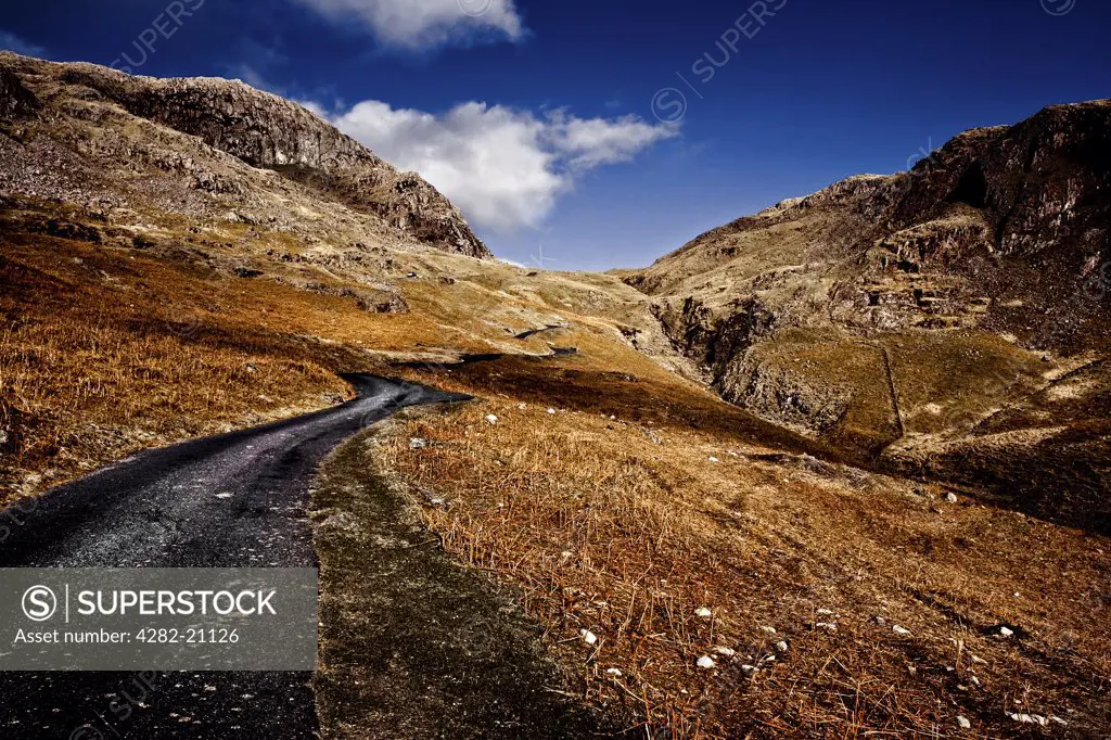 England, Cumbria, The Lake District. A view of mountains and a twisting road In Cumbria.