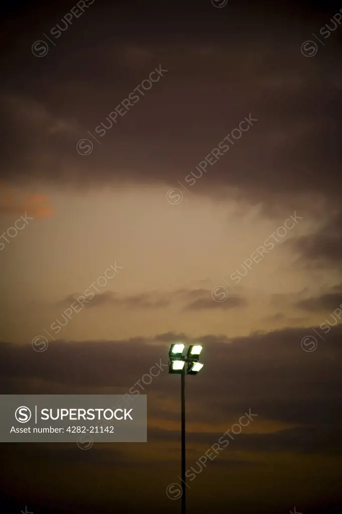 England, East Yorkshire, Goole. Illuminated floodlights below a dark gloomy sky in Goole.