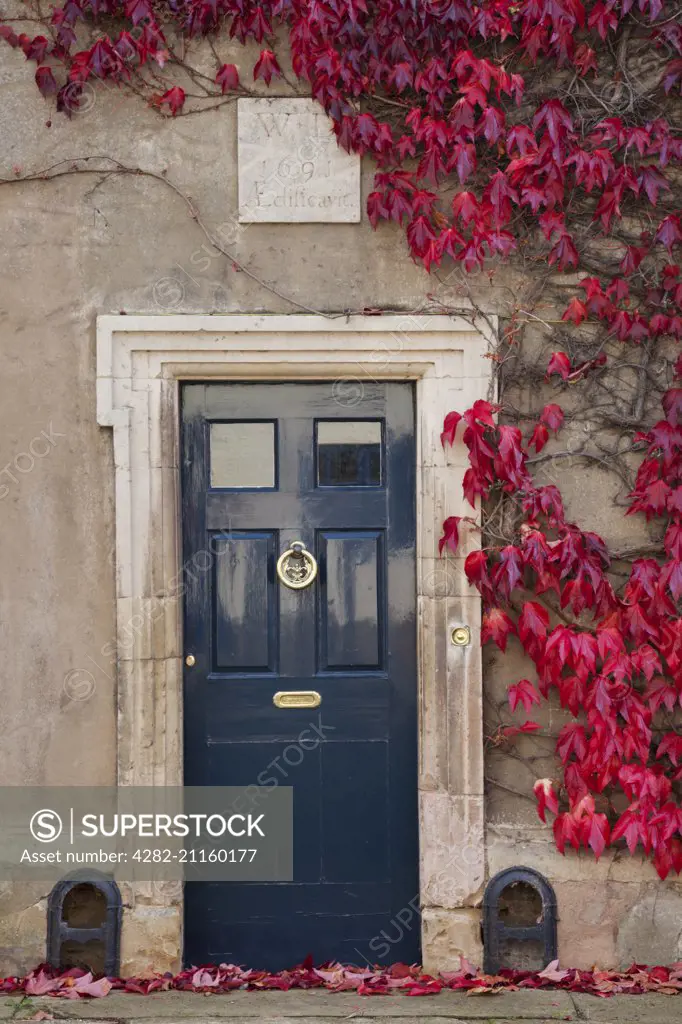 Virginia creeper frames the doorway of a house with a datestone of 1691 in Hallaton, in Leicestershire.
