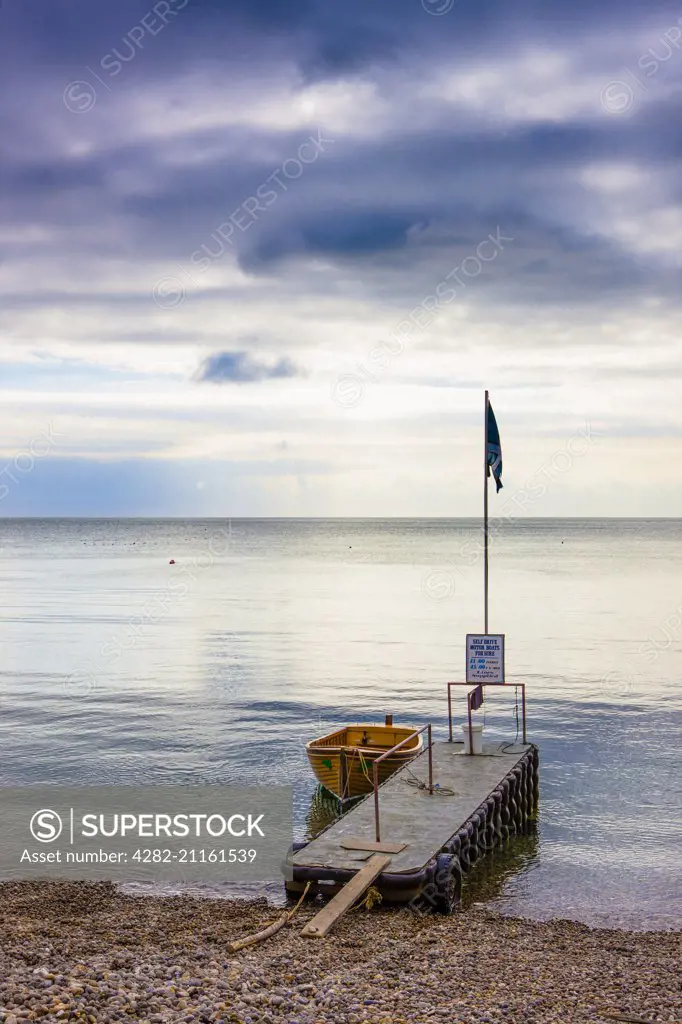 A dinghy tied up to a jetty on a calm morning.