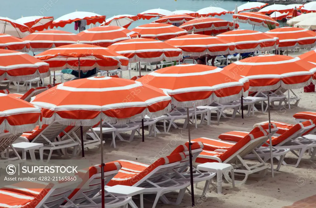 Beach umbrellas and sunloungers on the beach at Juan Les Pins on the Cote d'Azur in France.