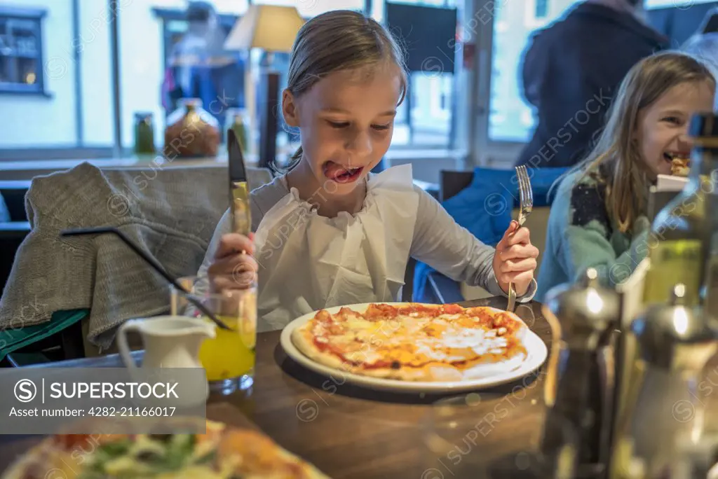 A child about to eat a delicious pizza in a restaurant.