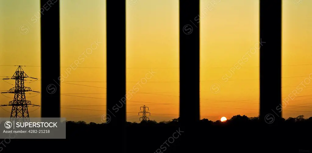 England, South Yorkshire, Sheffield. Silhouettes electric pylons and cables stretching across Sheffields landscape at sunset.