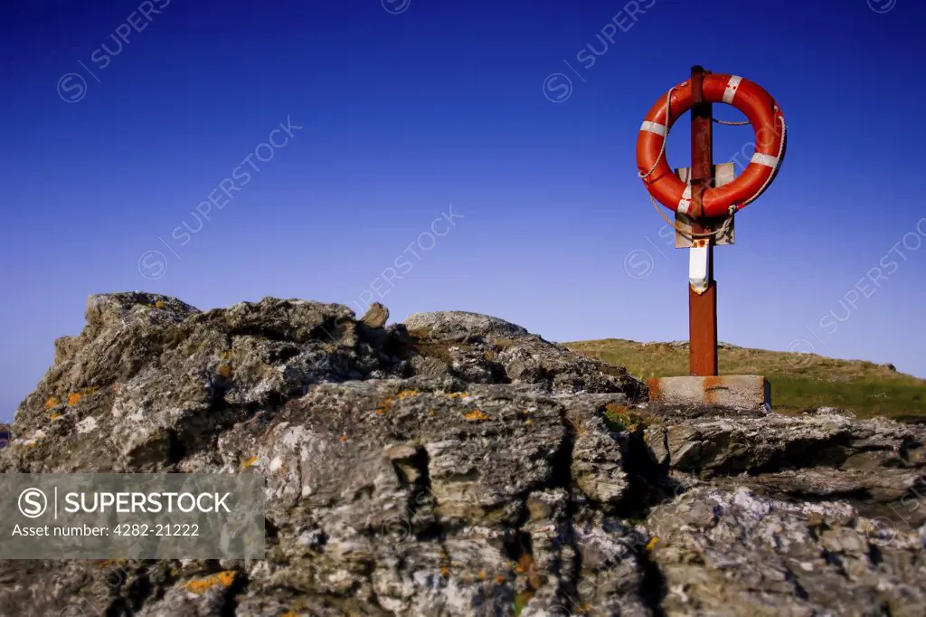 Wales, Anglesey, Holyhead. A red life ring and rocky outcrop on the coast at  Hollyhead.