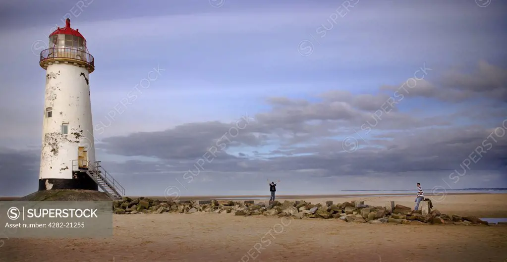 Wales, Denbighshire, Talacre. People climbing on the rocks at the foot of Talacre Lighthouse.