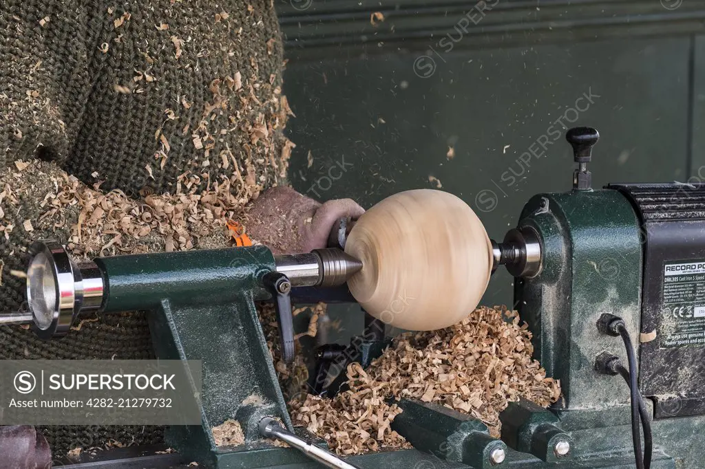 A wood turner turning a sphere on a lathe.
