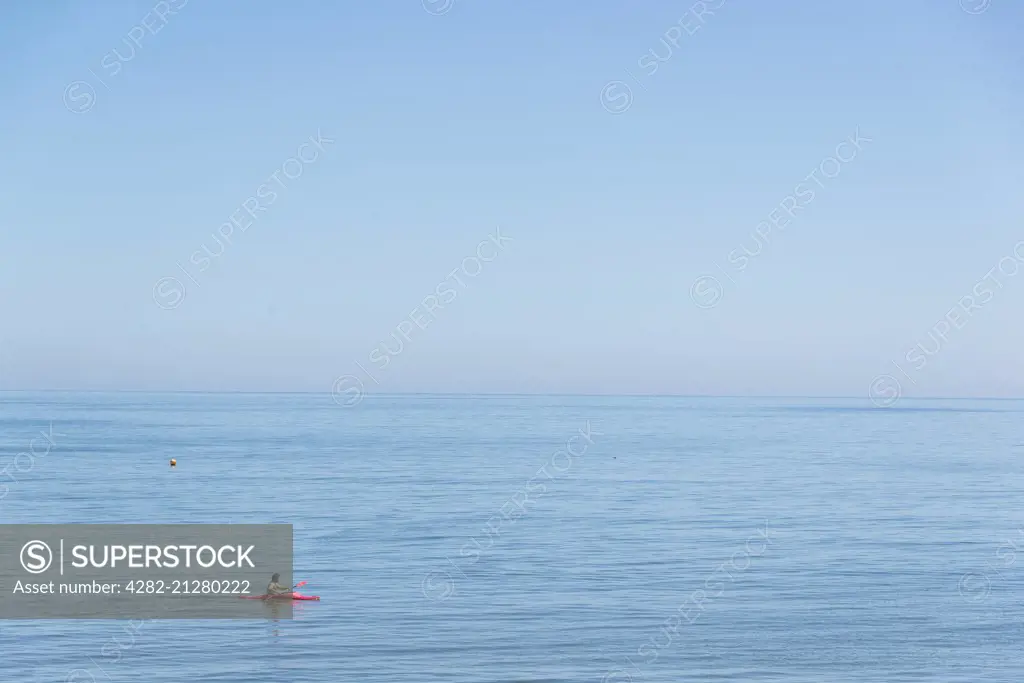 A man canoeing in a calm sea.