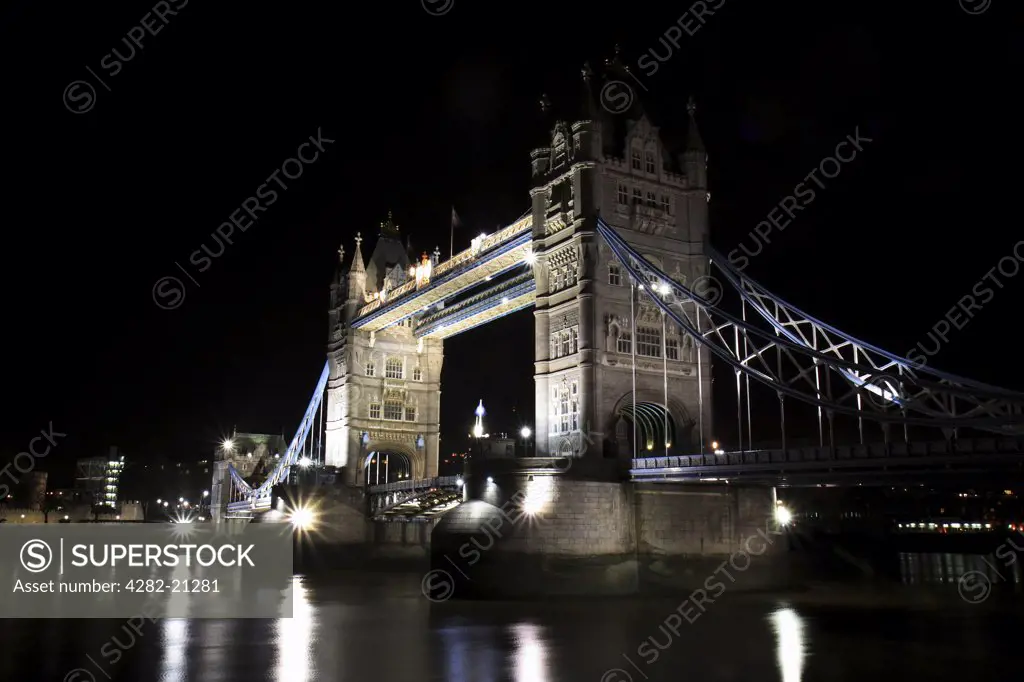England, London, Tower Bridge. A view over the Thames to an illuminated Tower Bridge at night.