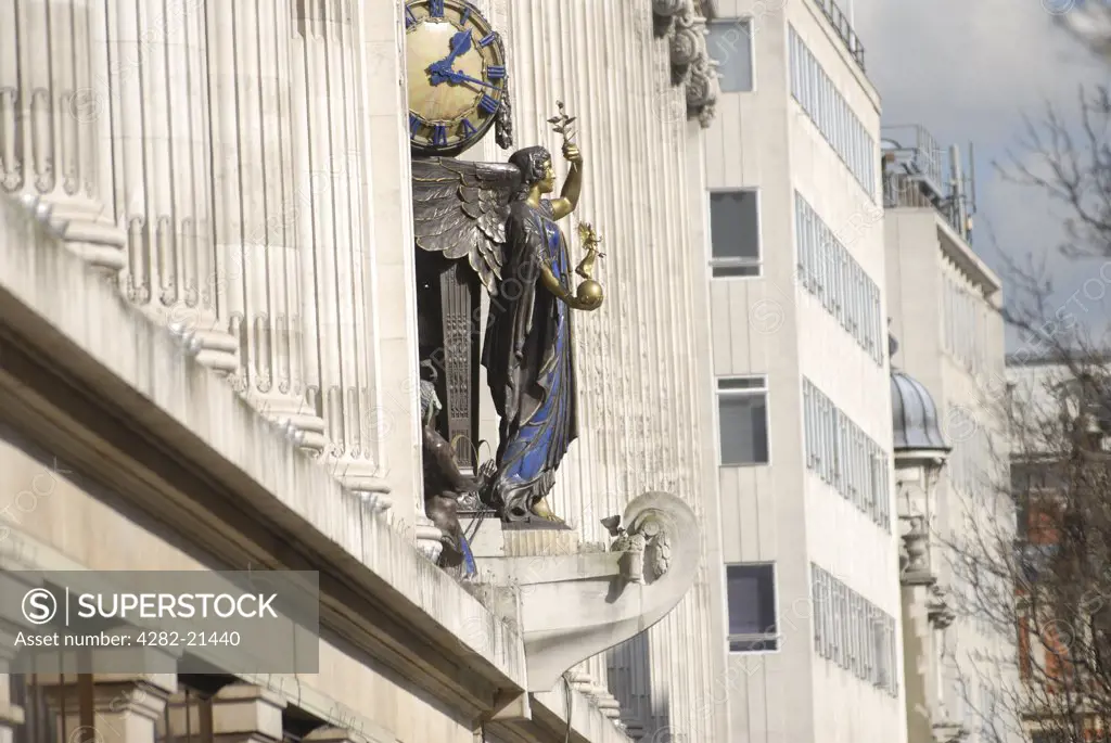 England, London, Oxford Street. Statue on Selfidges shop front. This art deco clock over the main entrance represents The Queen of Time standing in the stern of "" the trading ship"".