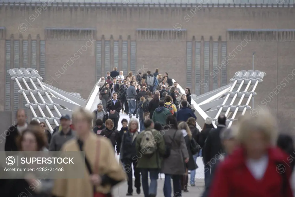 England, London, Millenium Bridge. People crossing the Millennium Bridge. The bridge is a 330m steel bridge linking the City of London at St. Paul's Cathedral with the Tate Modern Gallery at Bankside.