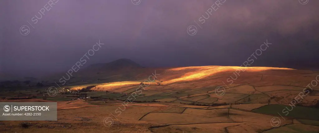 England, North Yorkshire, Pen-y-Ghent. Dramatic light strikes the lower slopes of Pen-y-Ghent in the Yorkshire Dales National Park. The view from Smearsett Scar also encompasses Ribblesdale and the Settle to Carlisle railway line.