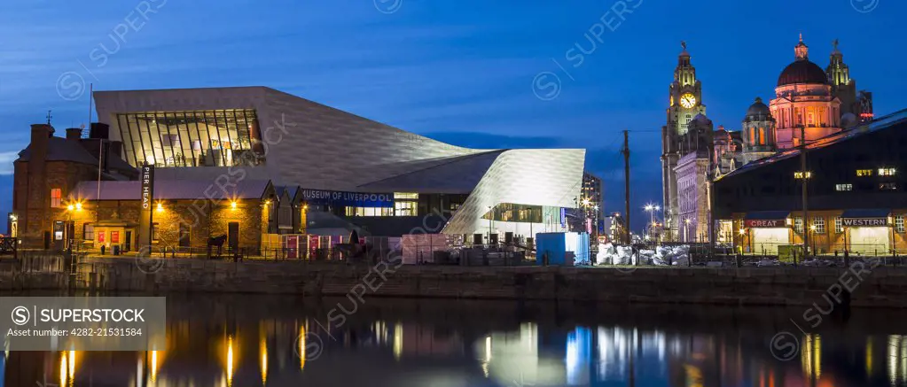 The Three Graces and the Museum of Liverpool lit up during twilight along Liverpool waterfront.