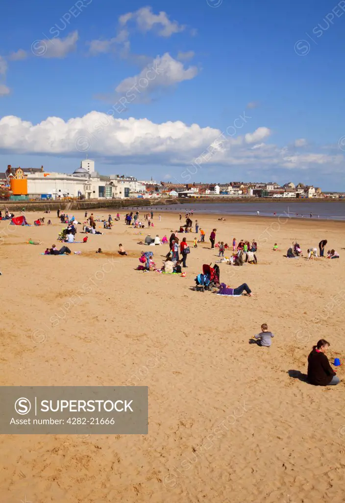 England, East Riding of Yorkshire, Bridlington. Holidaymakers enjoying the sun on Bridlington's South Beach with the Spa in the background.