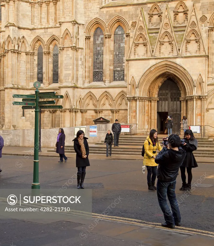 England, North Yorkshire, York. Asian tourists posing for photographs outside the South Transept of York Minster.