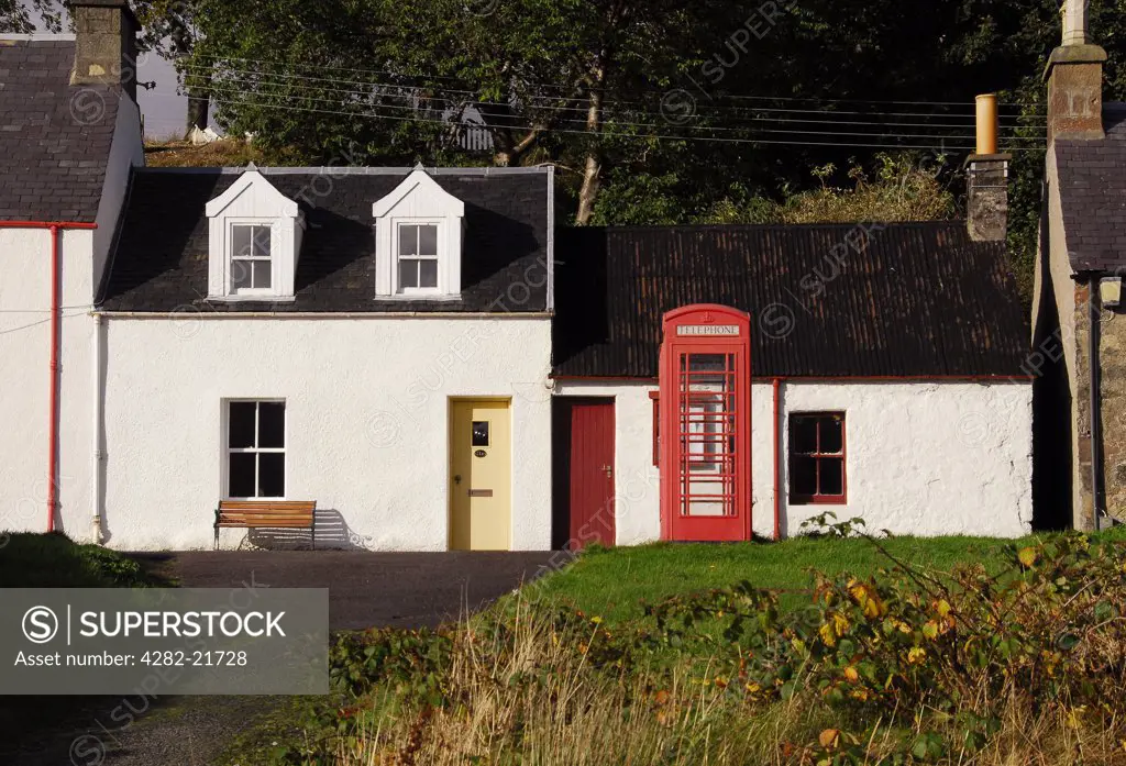 Scotland, Highland, Kyle of Lochalsh. Red telephone box with cottages in the village of Plockton. The village has National Trust conservation status.
