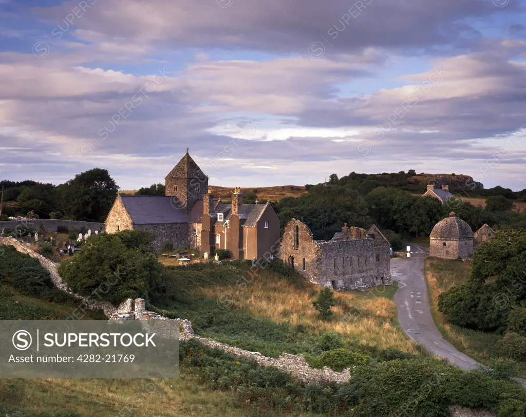 Wales, Anglesey, Beaumaris. Fading sunlight illuminates the remains on Penmon Priory and Priory church which serves as the parish church today.