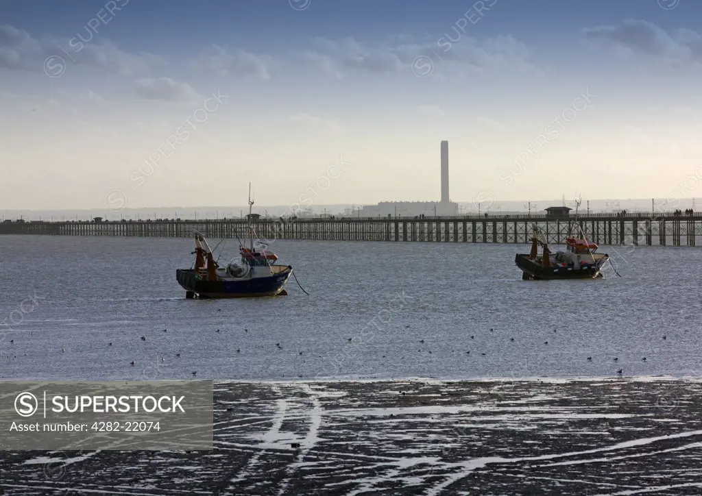 England, Essex, Southend-on-Sea. A view from the shore to fishing boats and Southend Pier.