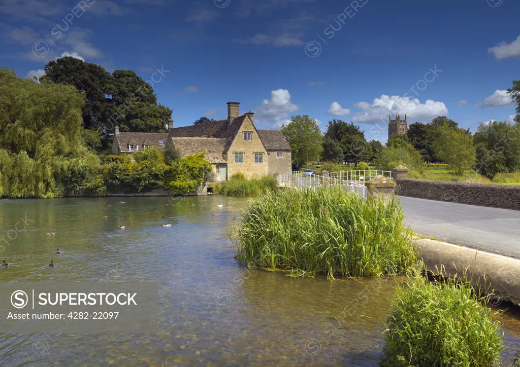 England, Gloucestershire, Fairford. Looking across the water to the mill at Fairford in Gloucestershire.