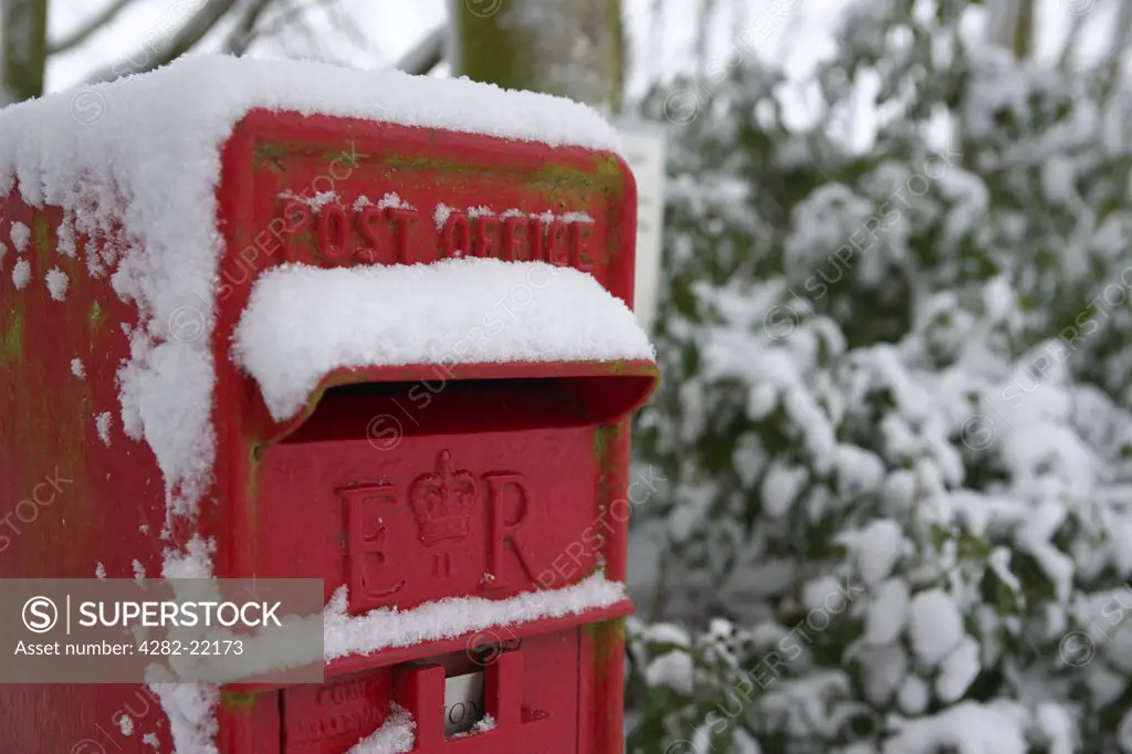England, Essex, Saffron Walden. Snow covers a traditional British rural post box in Essex.