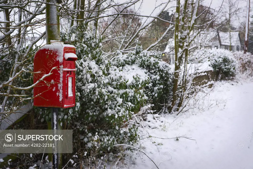 England, Essex, Saffron Walden. A winter scene with snow covering a red post box in Saffron Walden.