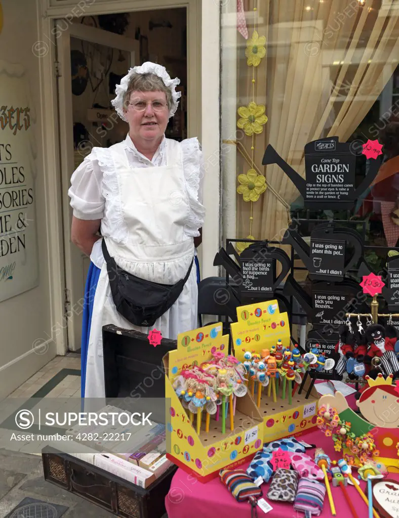 England, Kent, Rochester. A shopkeeper wearing a Victorian costume standing by her wares at the Dickens Festival 2010.