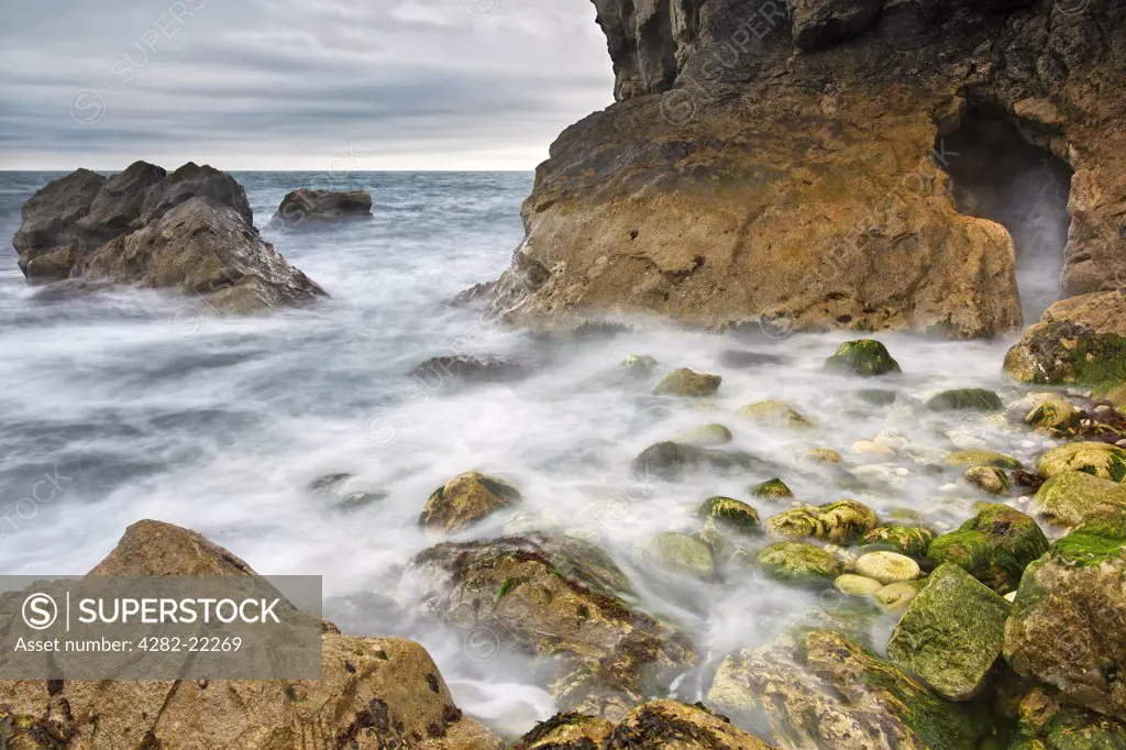 England, Dorset, Lulworth. Sea swirling in and around rocks in Stair Hole, a relatively new cove that is forming just to the west of Lulworth Cove in Dorset, southern England.