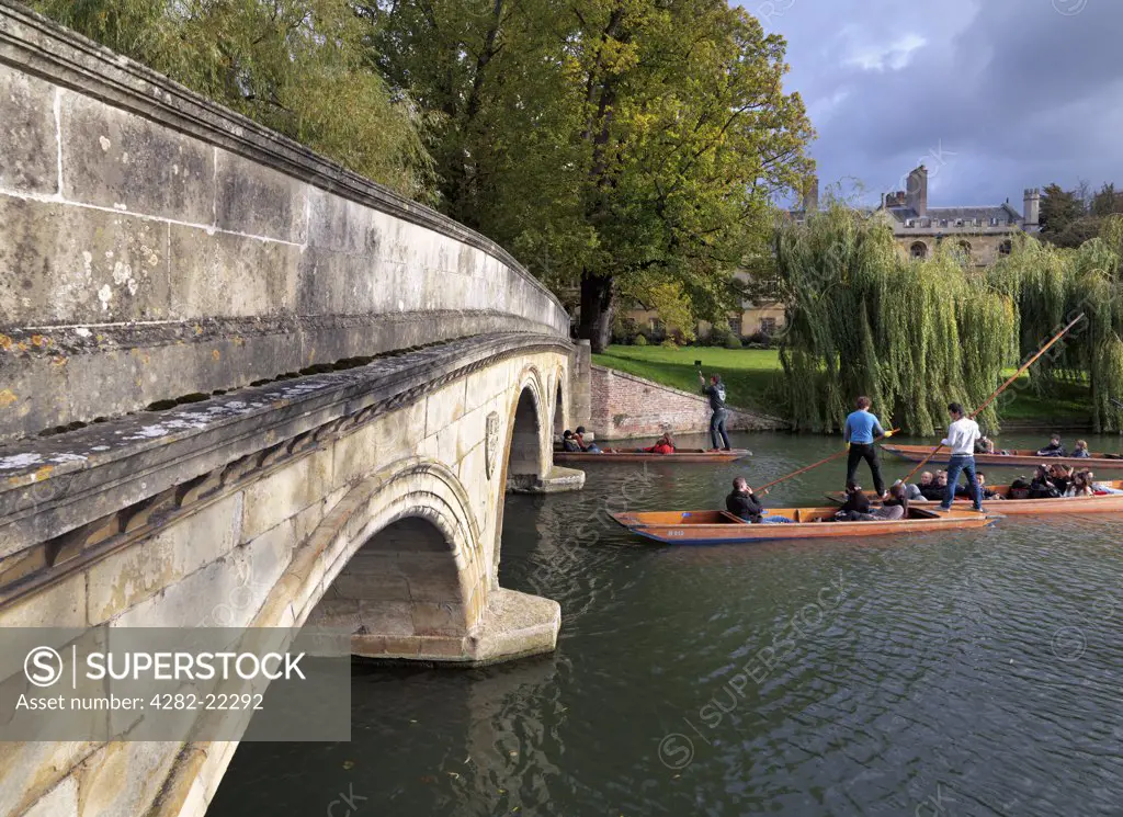 England, Cambridgeshire, Cambridge. Tourists enjoying a sightseeing trip along the River Cam in a punt at Trinity College Bridge.