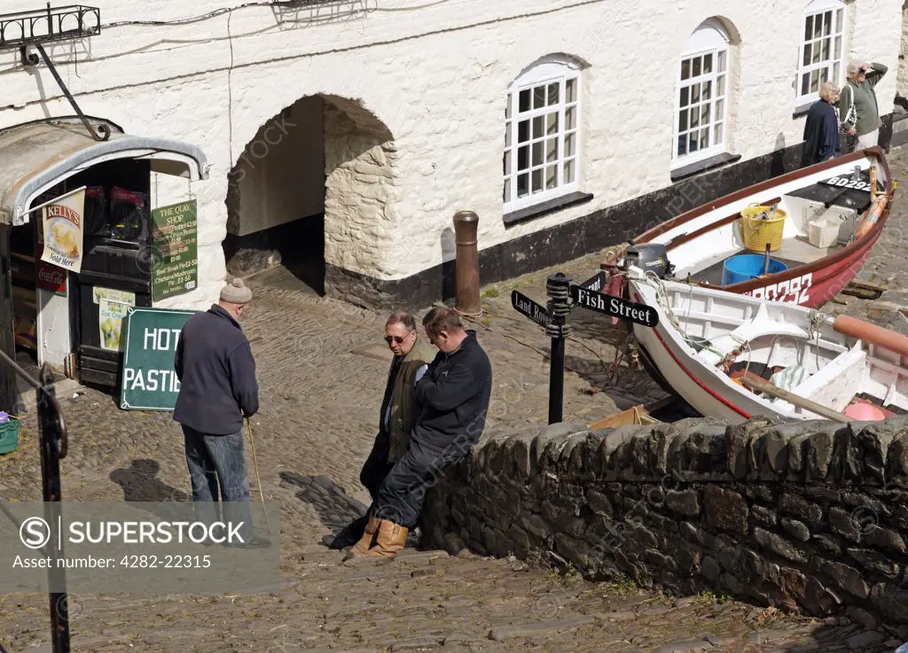 England, Devon, Clovelly. Locals in conversation at the foot of steps in the famous, historic, fishing village of Clovelly in North Devon.