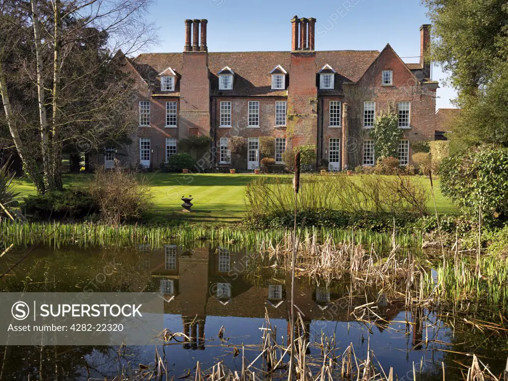 England, Suffolk, Hintlesham. The rear of Hintlesham Hall, a stunning 16th century Elizabethan Grade I listed country house hotel, reflected in a pond in the gardens.