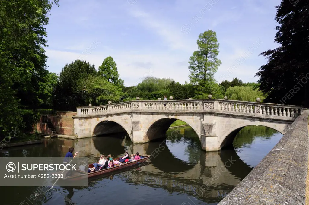 England, Cambridgeshire, Cambridge. Tourists enjoying a trip along the River Cam, about to go under Clare bridge in a punt.