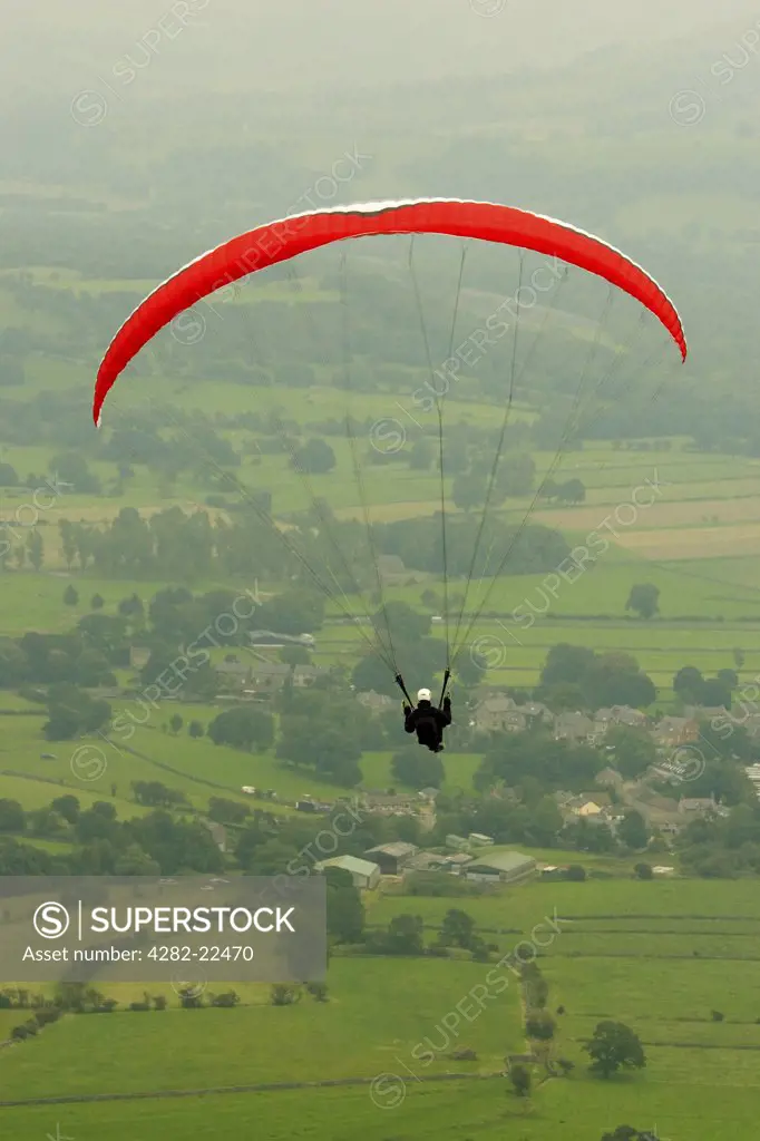 England, Derbyshire, Hope valley. A man paragliding over the Hope Valley in Derbyshire.