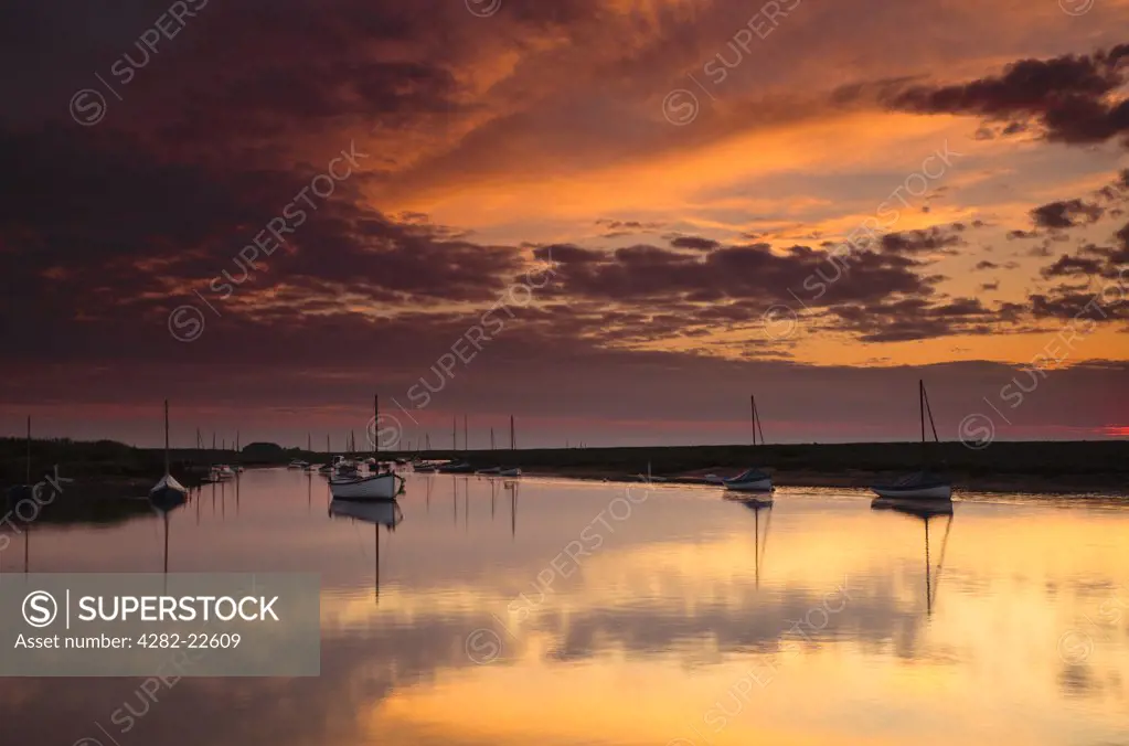 England, Norfolk, Burnham Overy Staithe. Red sky over boats moored in the harbour at Burnham Overy Staithe in Norfolk.