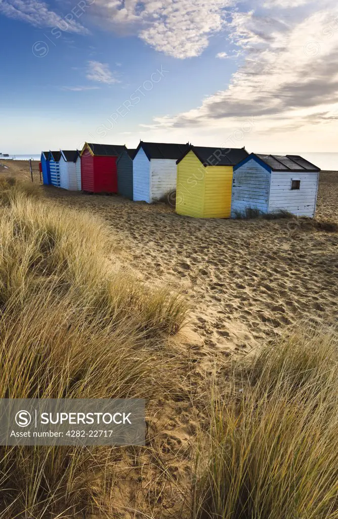 England, Suffolk, Southwold. Beach huts at Southwold viewed from the grassy sand dunes.