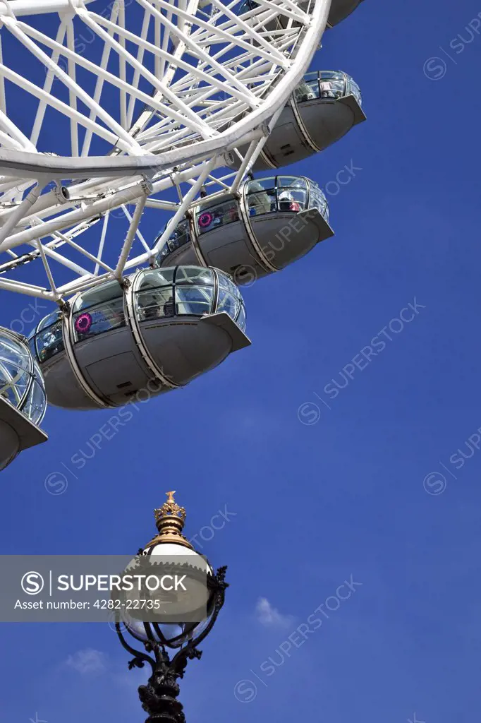 England, London, South Bank. Pods on the London Eye and a Victorian street lamp against a deep blue sky.