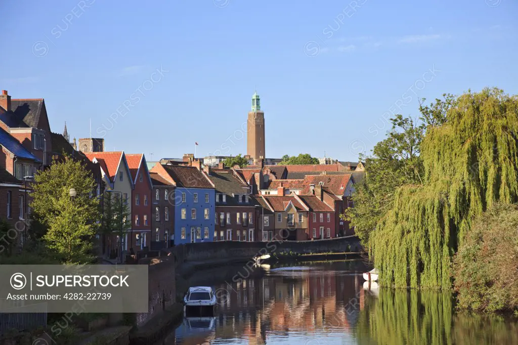 England, Norfolk, Norwich. Refurbished houses by the River Yare in Norwich showing the clock tower of Norwich City hall in the background.