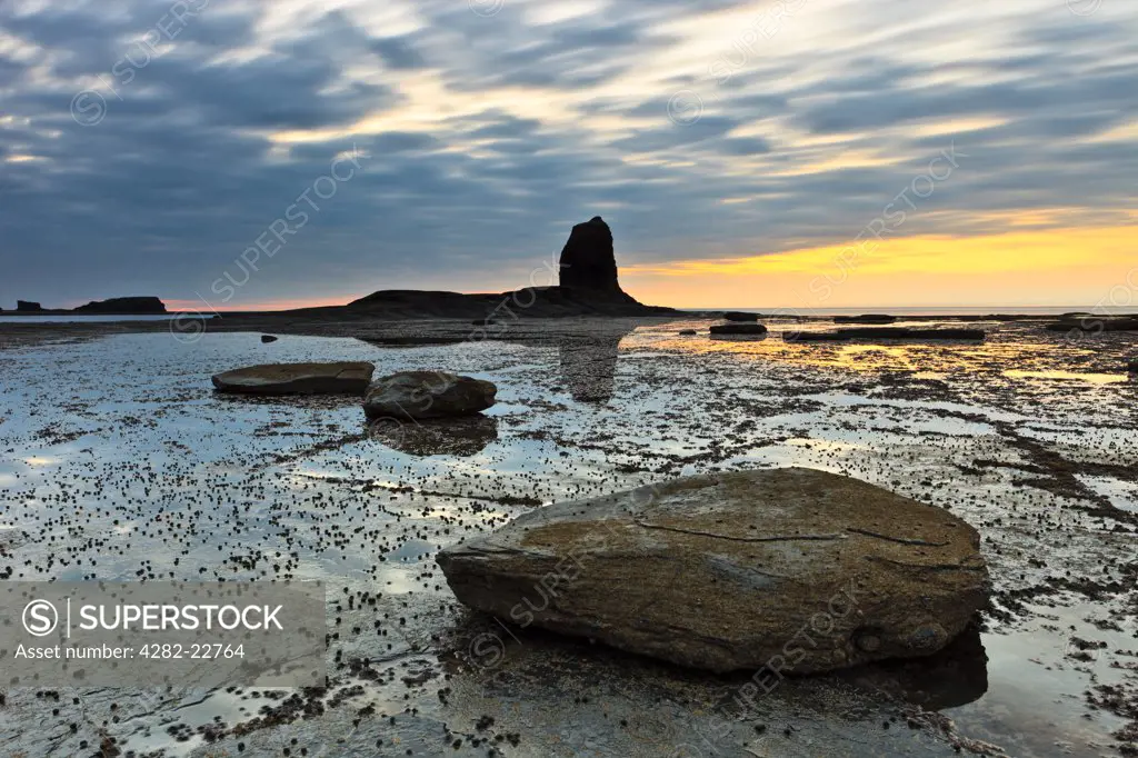 England, North Yorkshire, Whitby. Sunset over Black Nab in Saltwick Bay at low tide.