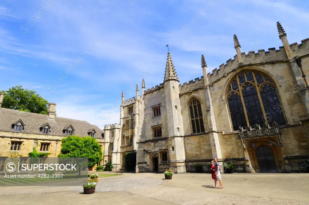England, Oxfordshire, Oxford. A couple sightseeing in St John's Quad outside the Chapel, Founder's Tower and Presidents Lodgings at Magdalen College, one of the constituent colleges of the University of Oxford.