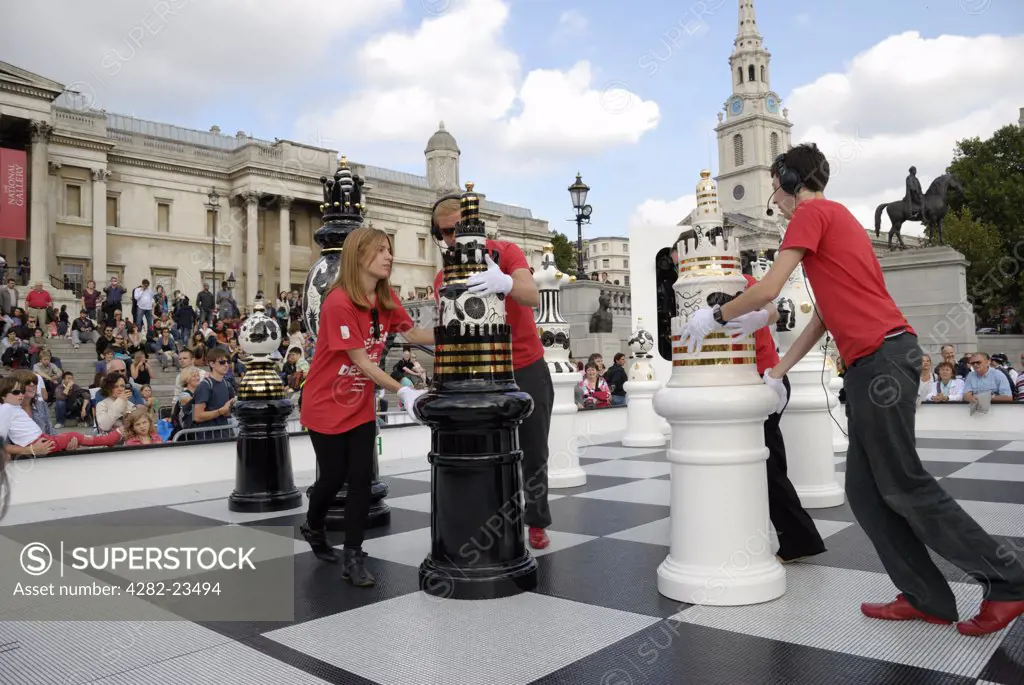 England, London, Trafalgar Square. Helpers moving giant chess pieces as part of The Tournament, an installation created for the 2009 London Design Festival in Trafalgar Square.