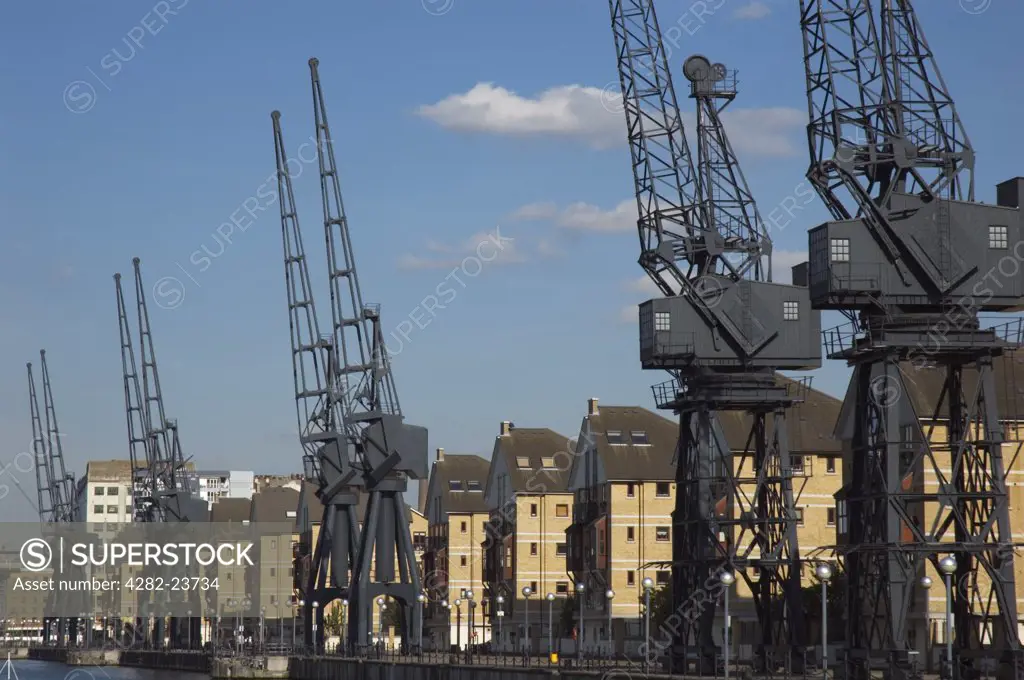 England, London, Docklands. Houses and disused cranes at Britannia Village next to Royal Victoria Dock.