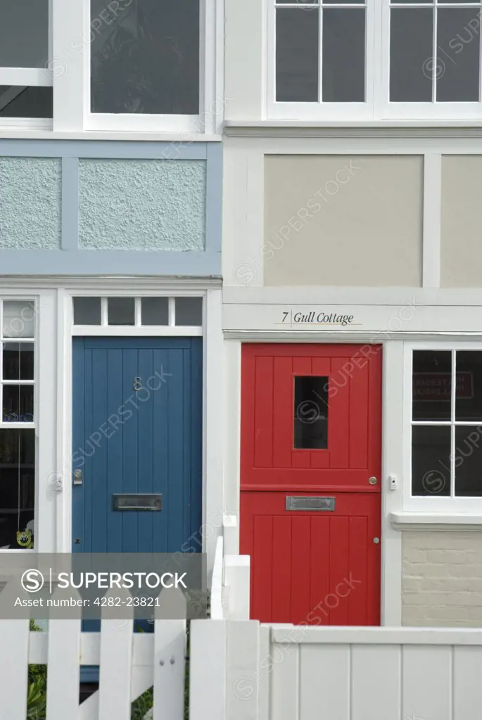 England, Kent, Whitstable. Close up of two terraced cottages with red and blue doors in Whitstable.